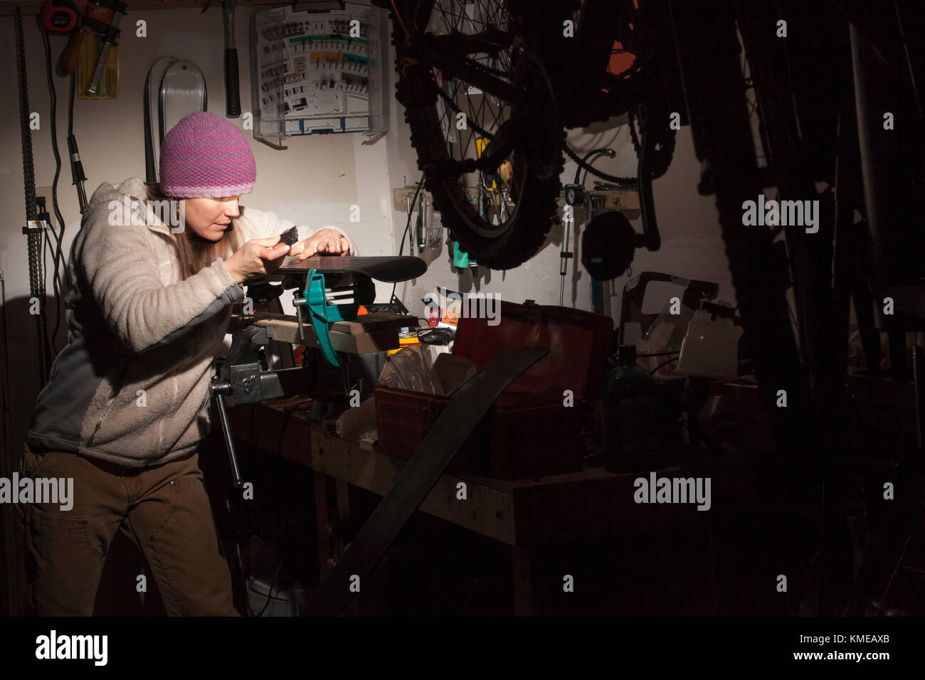 Woman in knit hat tuning skis in garage, Missoula, Montana, USA Stock Photo