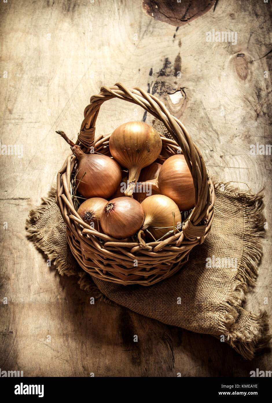 Fresh onion in an old basket. On wooden background. Stock Photo