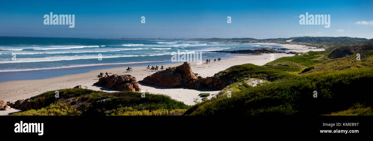 Panoramic view with people riding horses in distance on beach at Post Office Rock,Marrawah,Tasmania,Australia Stock Photo