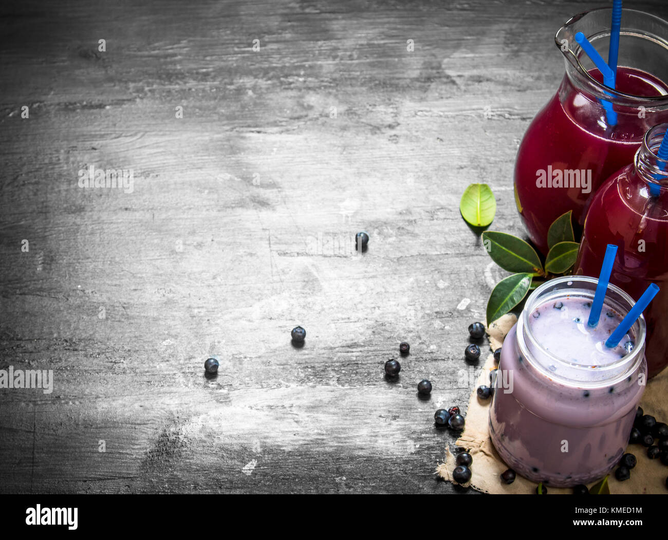 Blueberry smoothies and fresh juice on the old fabric. On a black wooden background. Stock Photo