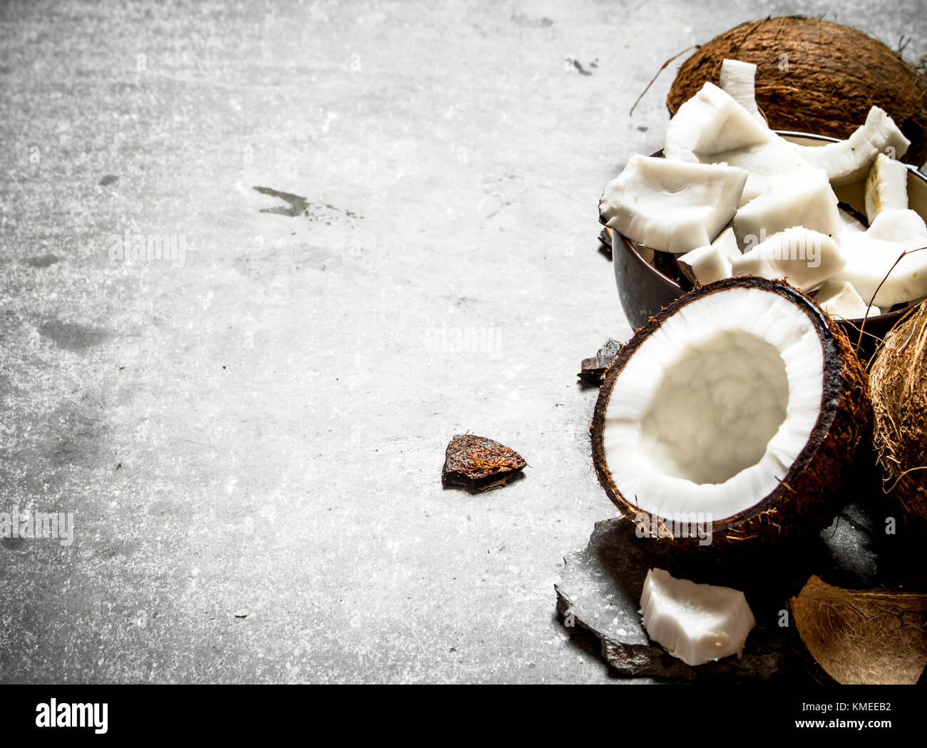 Coconut pulp in a bowl and whole coconuts. On a stone background Stock