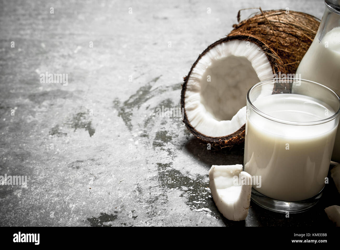 Coconut milk in a jar with pieces of coconut. On a stone background