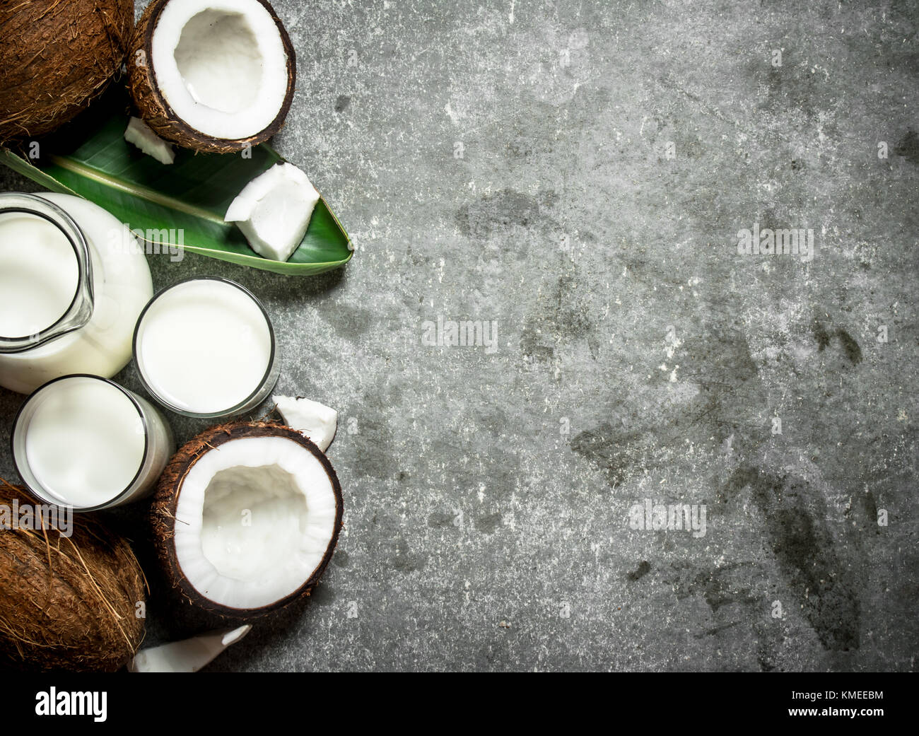 Coconut milk in a jar with pieces of coconut. On a stone background