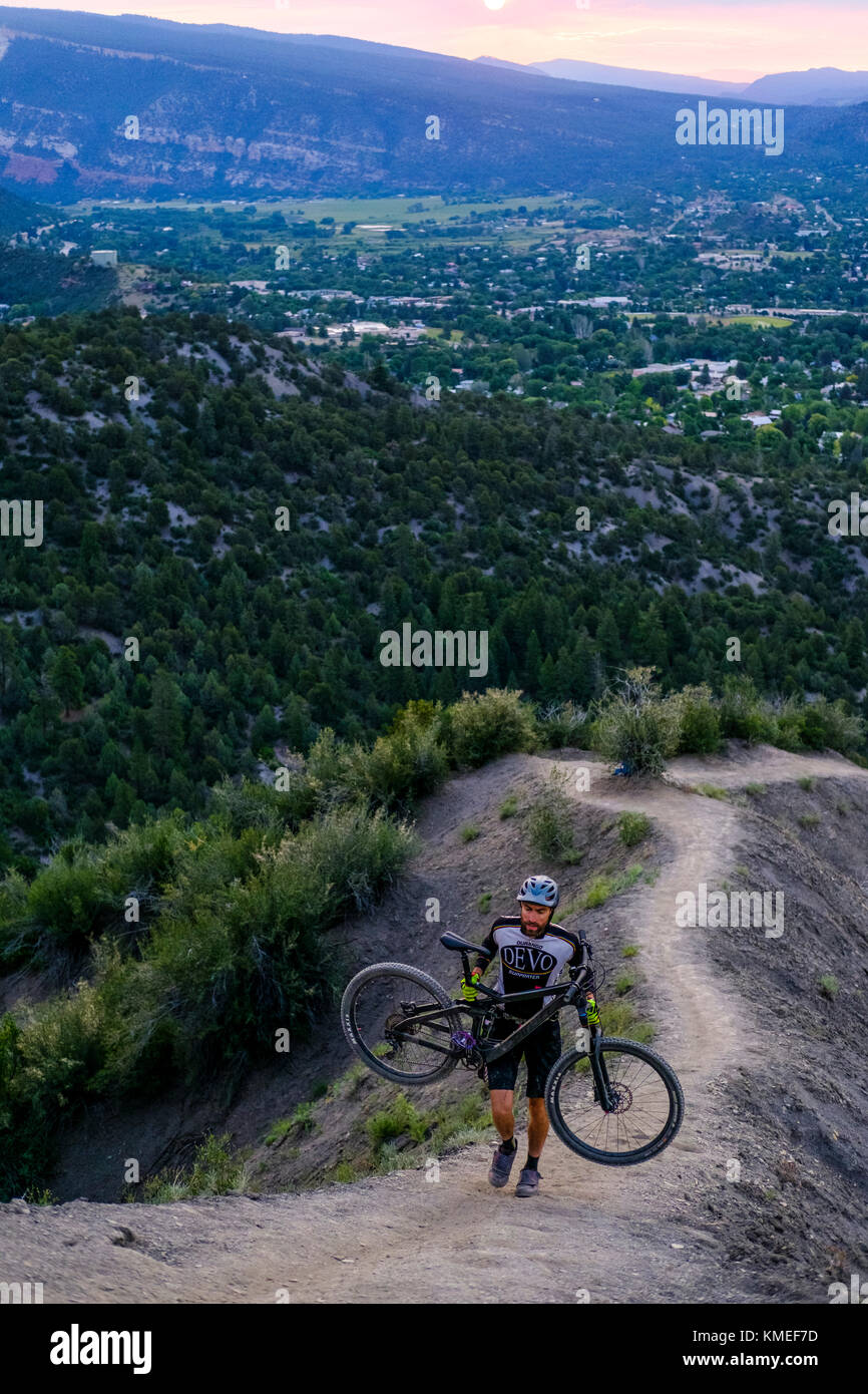 Male Mountain Biker in scenic landscape carries bike up Hogs back near Durango,Colorado,USA