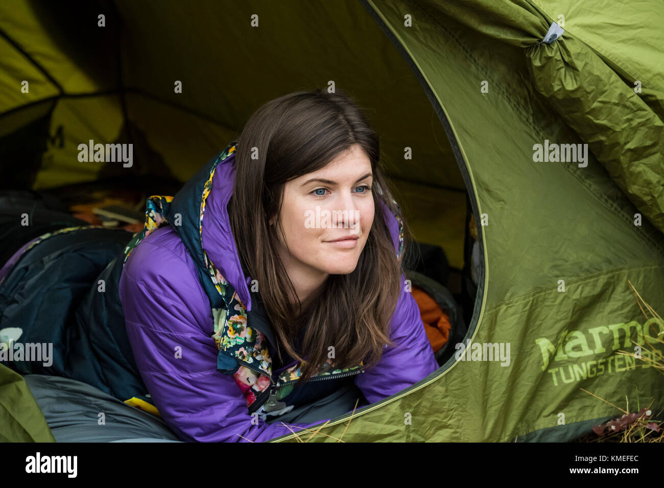 Female camper with long black hair lying on front and looking out of tent,Jackson,Wyoming,USA Stock Photo