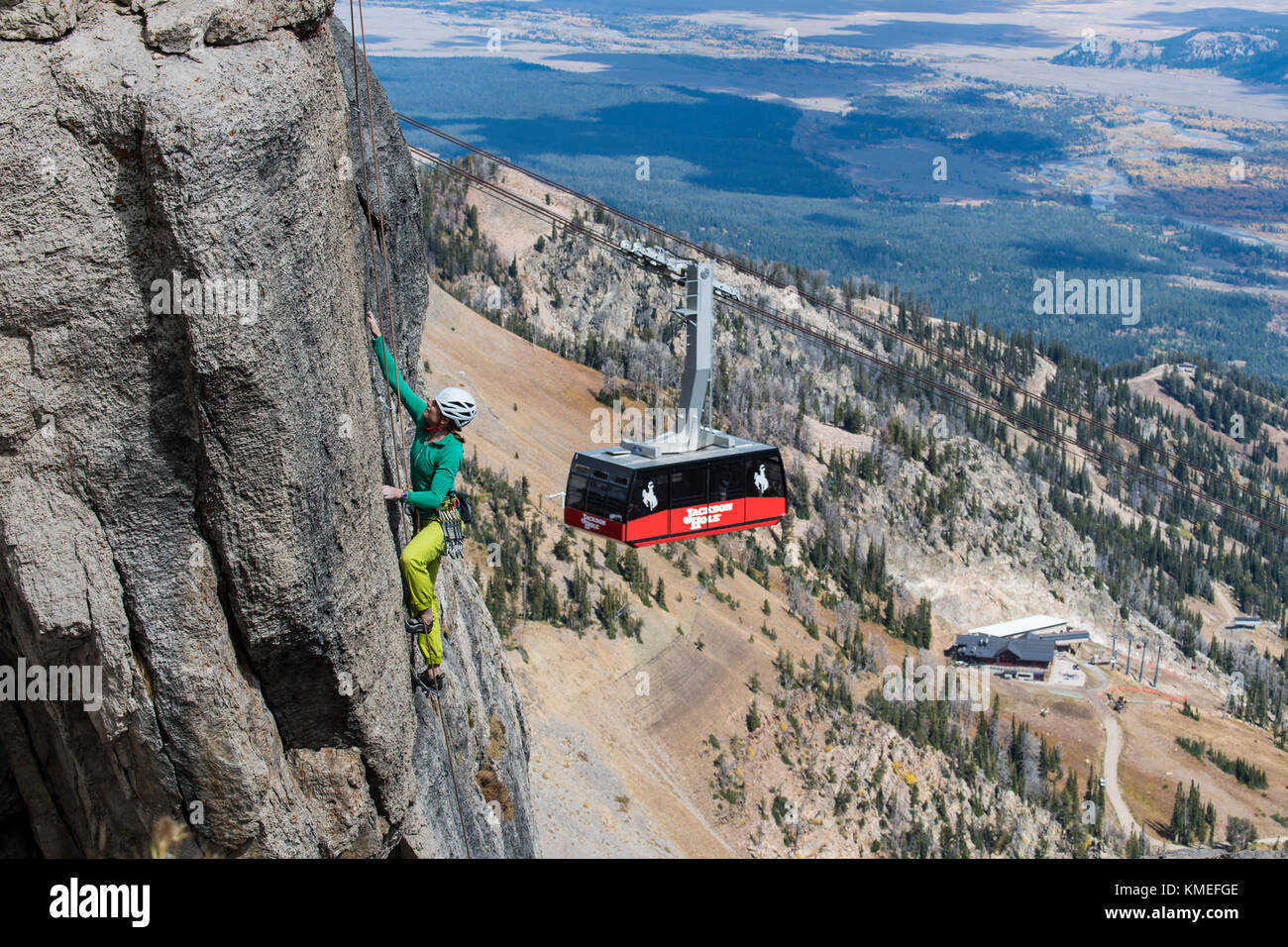 Female climber climbing rock face with mountains and Jackson Hole