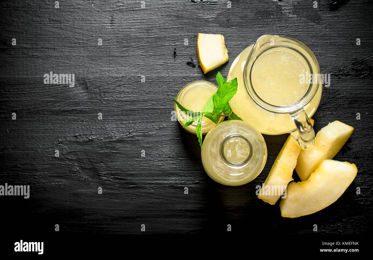 Fresh juice of a melon with branches of fresh mint. On the black wooden table. Stock Photo