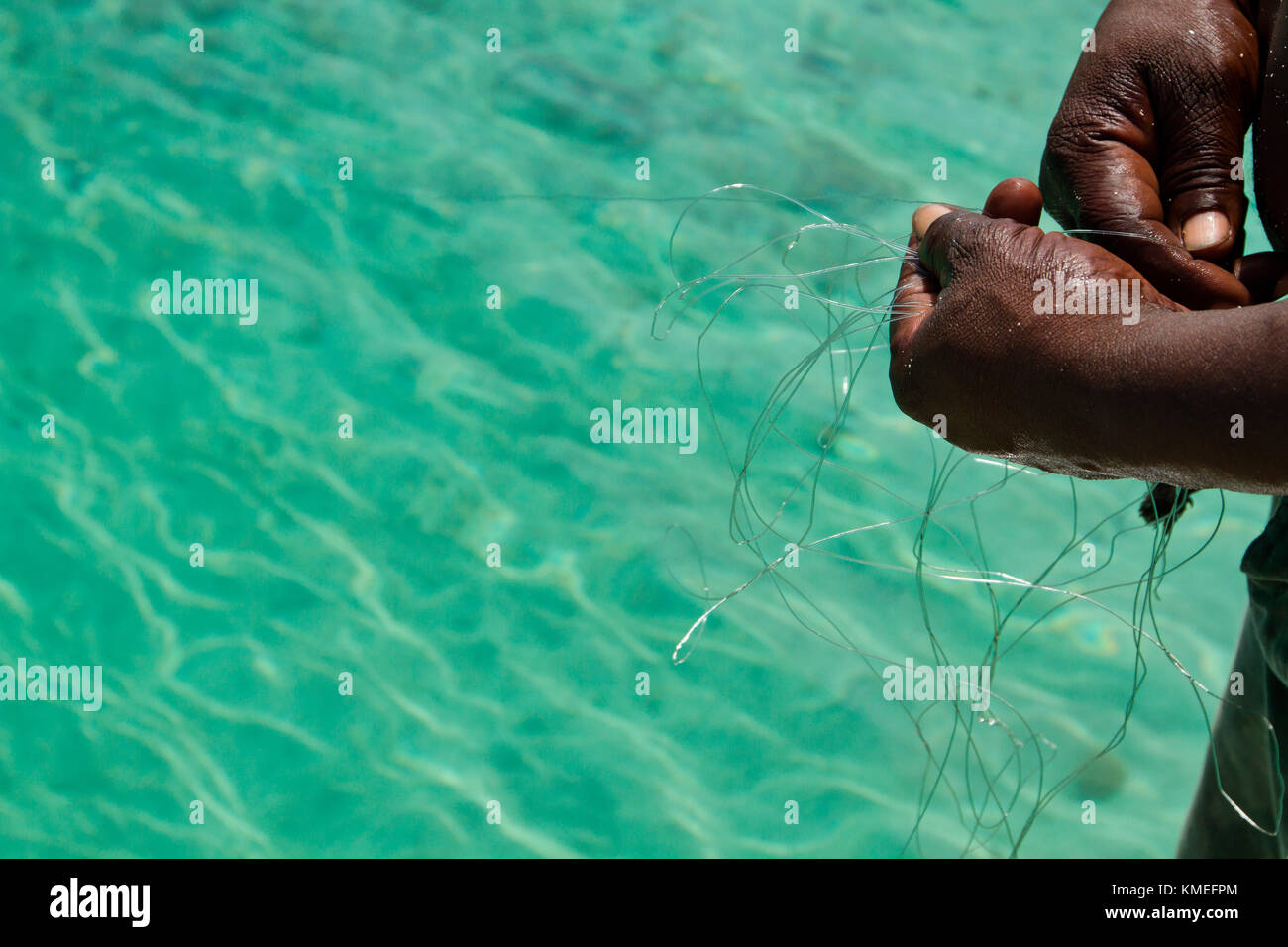 Close up of hands of man holding fishing line, Isla Marisol, Belize Stock Photo