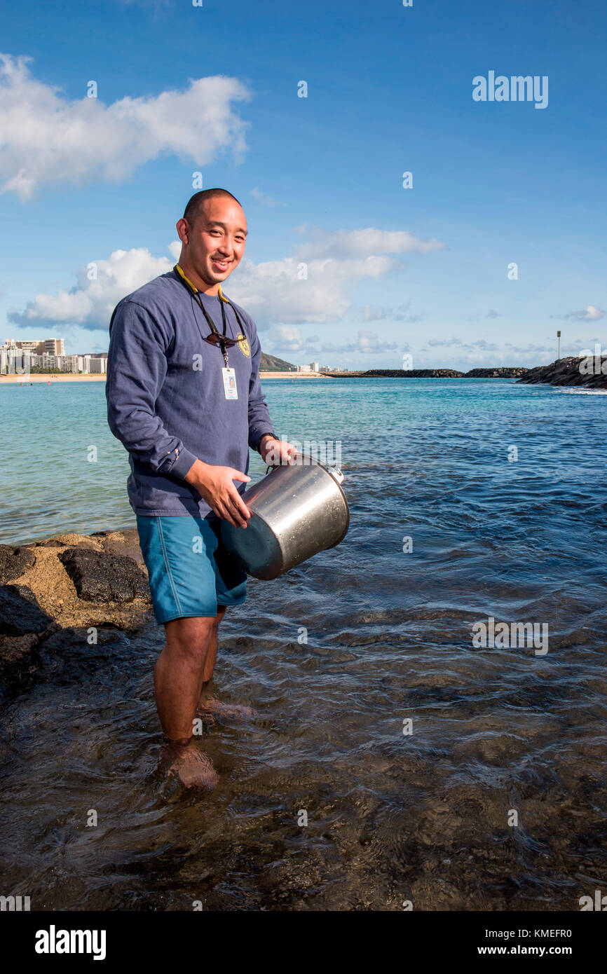 Wataru Kumagai of the State of Hawaii Department of Health Clean Water Branch,demonstrates water sampling of Hawaiian beaches at Ala Moana Beach in Honolulu using instruments such as a turbidity meter.For the full scope of readings,lab work has be done offsite. Stock Photo