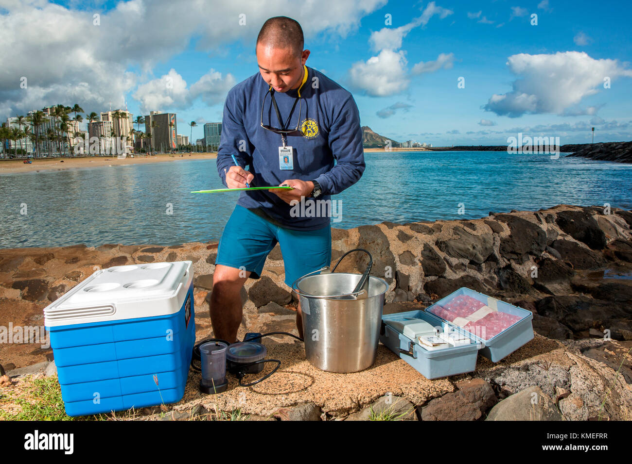 Wataru Kumagai of the State of Hawaii Department of Health Clean Water Branch,demonstrates water sampling of Hawaiian beaches at Ala Moana Beach in Honolulu using instruments such as a turbidity meter.For the full scope of readings,lab work has be done offsite. Stock Photo