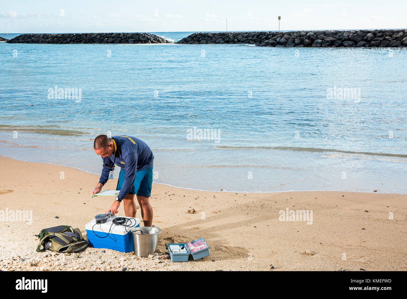 Wataru Kumagai of the State of Hawaii Department of Health Clean Water Branch,demonstrates water sampling of Hawaiian beaches at Ala Moana Beach in Honolulu using instruments such as a turbidity meter.For the full scope of readings,lab work has be done offsite. Stock Photo