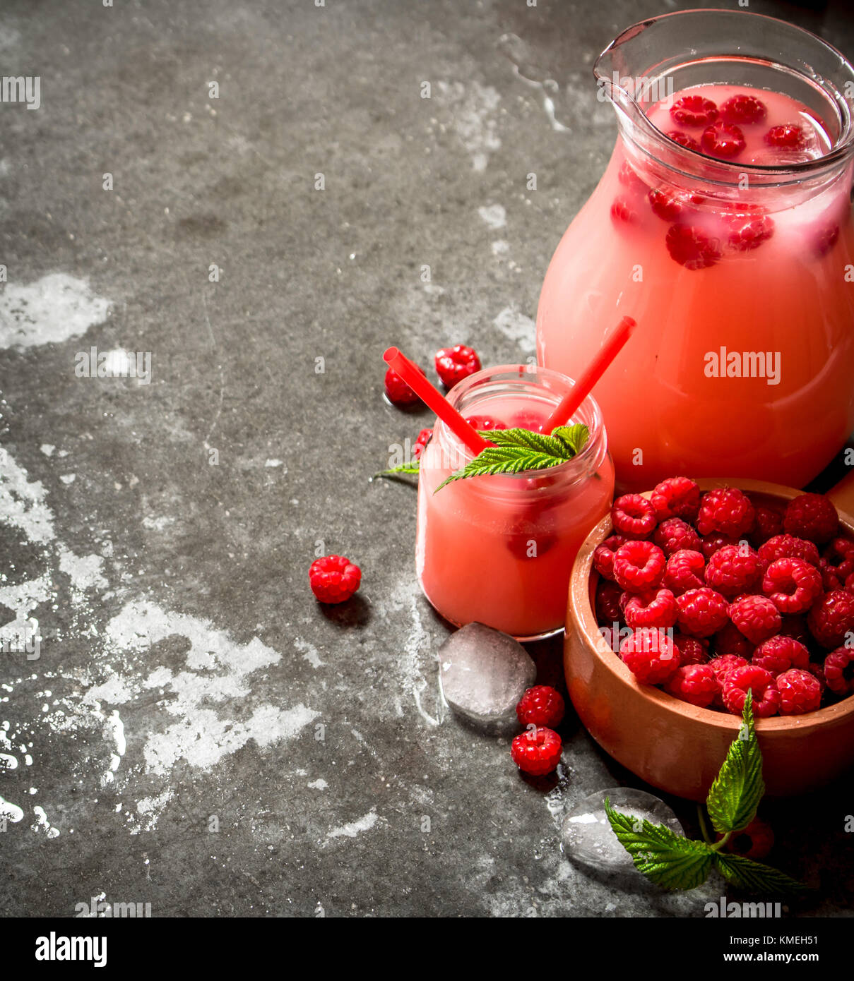Raspberry juice with the berries and ice. On the stone table Stock ...