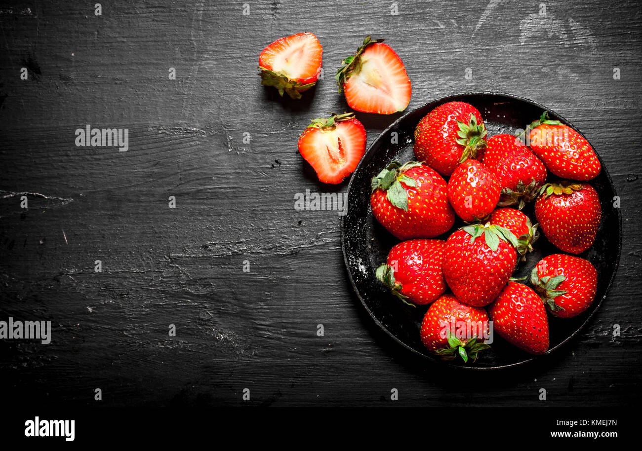 Ripe strawberries old plate. On the black wooden table Stock Photo - Alamy