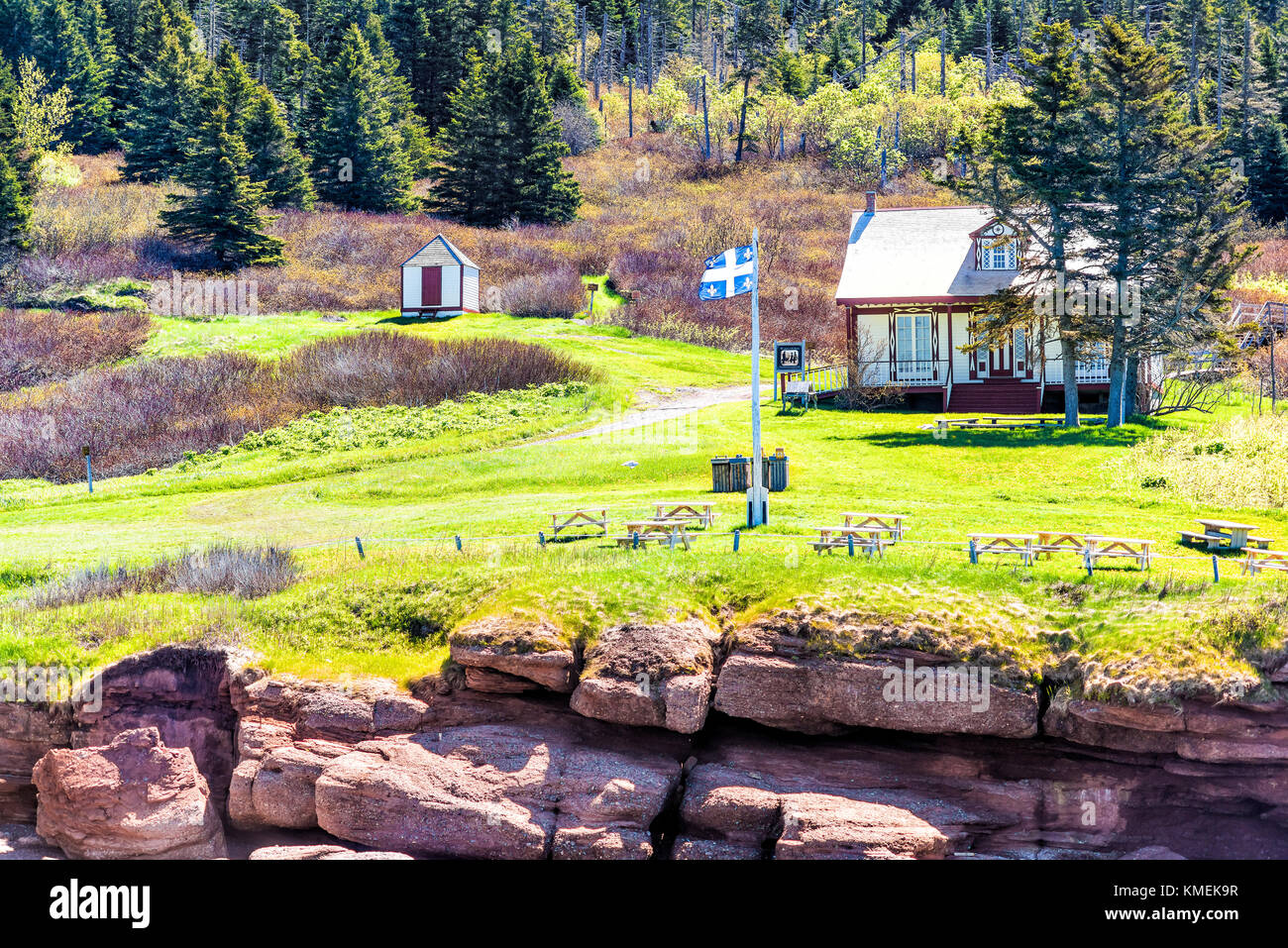 Bonaventure Island Park entrance with houses and green meadows, blue Quebec flag Stock Photo