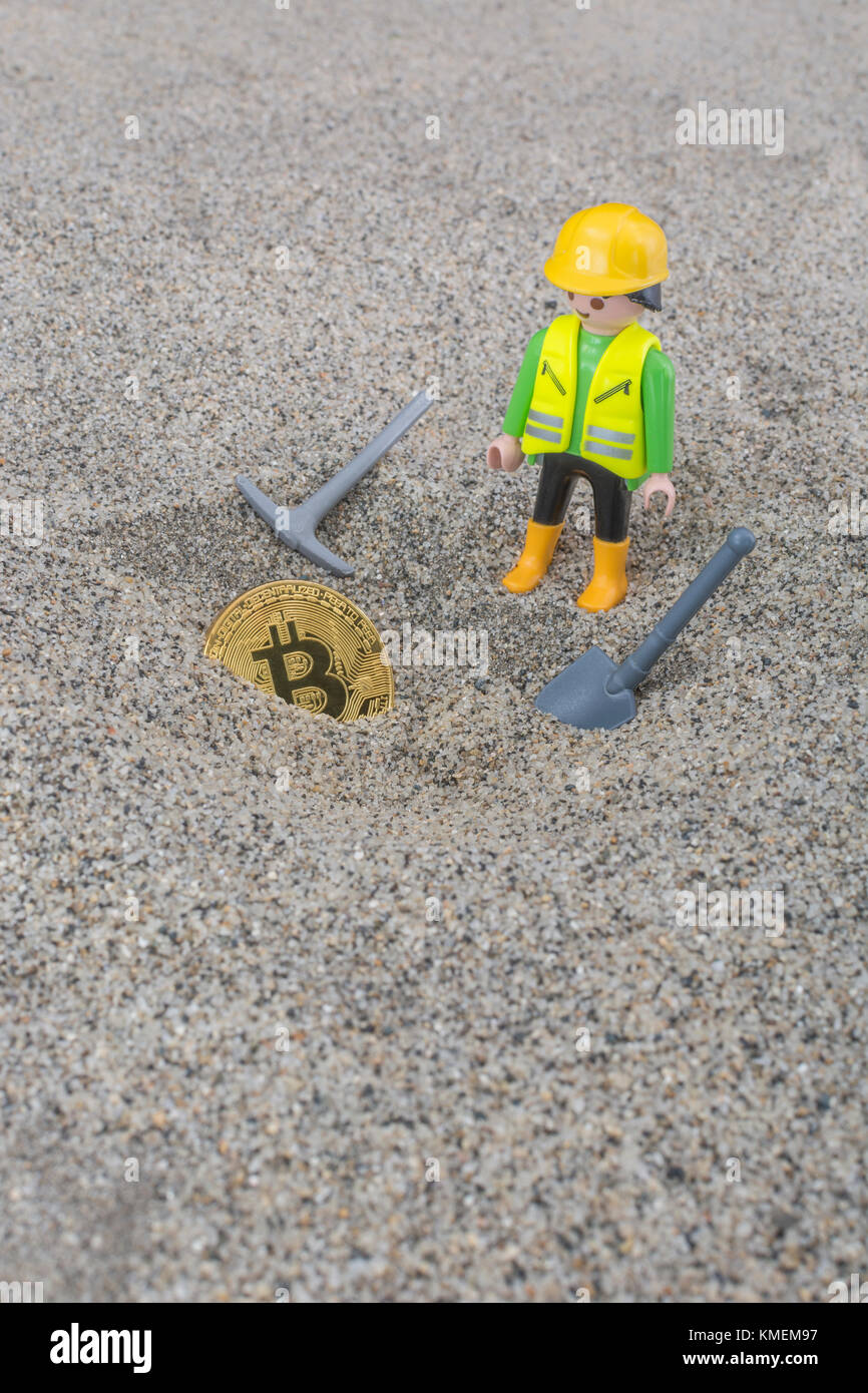 Playmobil character in imaginary mining of gold-colored Bitcoin cyber / cryptocurrency - Bitcoins value reaching high levels in December 2017. Stock Photo