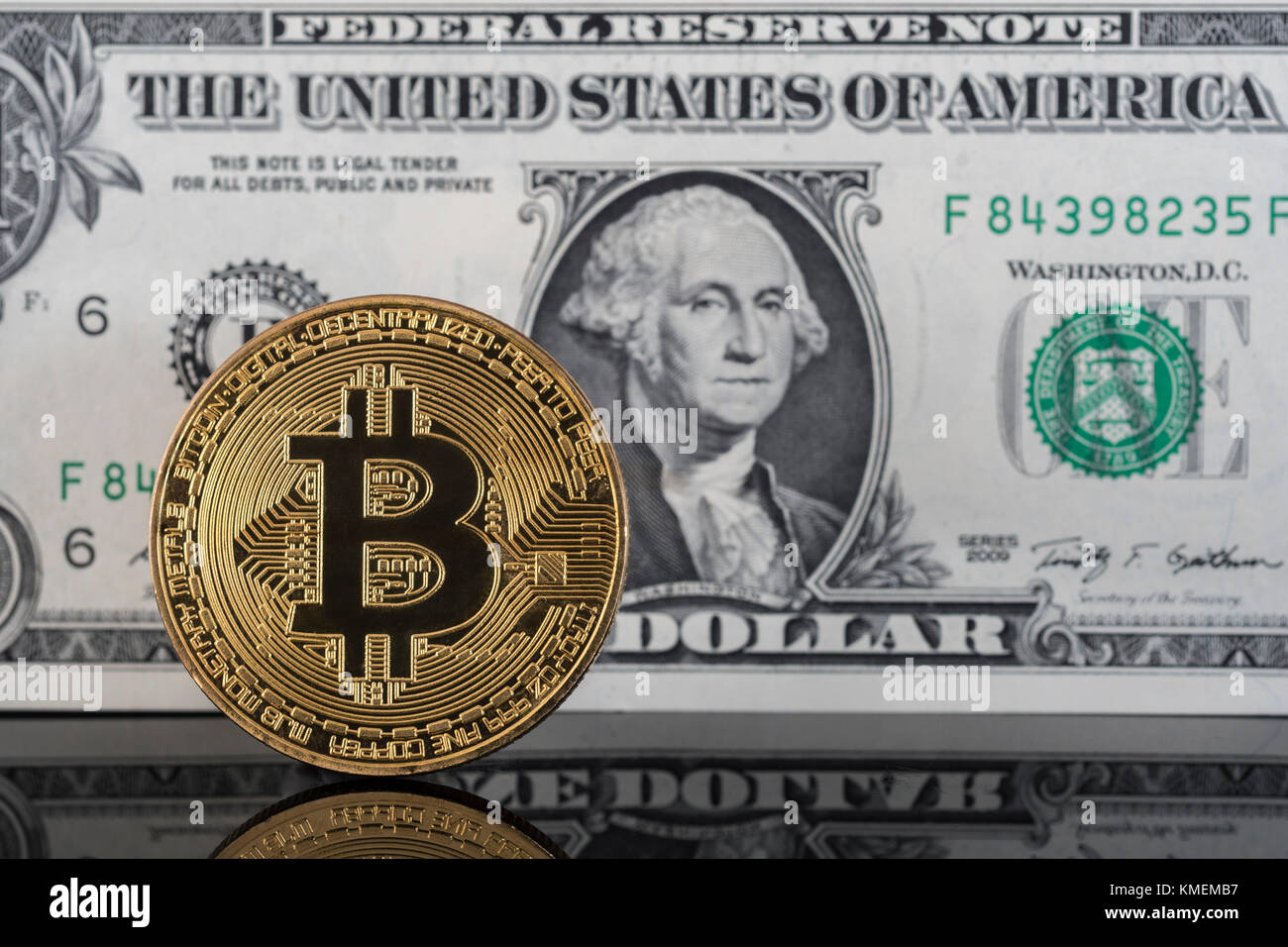 Gold-colored Bitcoin cryptocurrency with US $1 bills / banknotes - Bitcoin values reaching high levels in December 2017, 2020 Bitcoin crash. Stock Photo