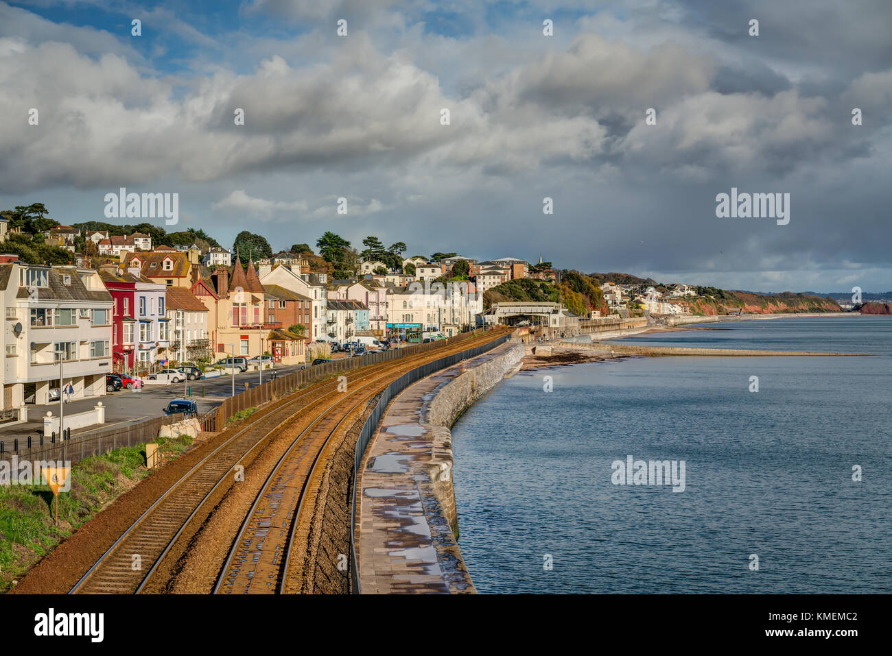 An English seaside landscape of Dawlish town, Devon, separated from the blue sea by the rusted railway lines which lead through. A blustery sunny day. Stock Photo