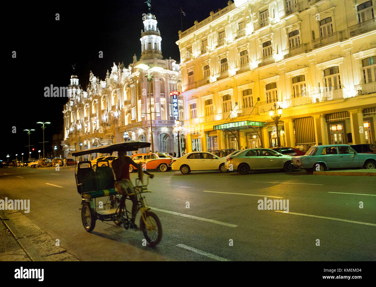 Different generations of transportation on street in Havana near the Great Theatre of Havana Alicia Alonso.  One sees a pedicab, some modern models of automobiles and some classic 1950 and 1960's American automobiles. Stock Photo