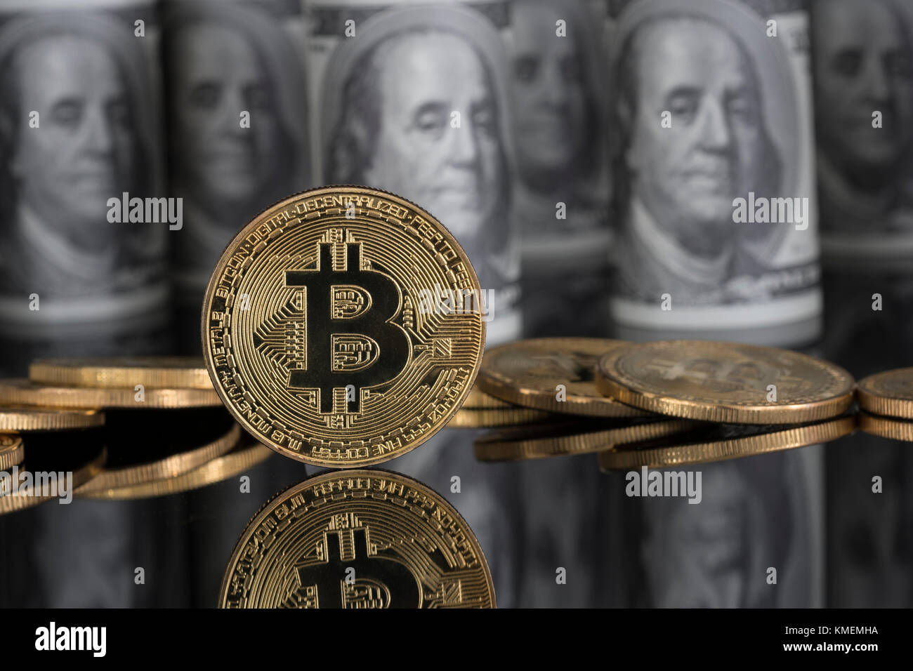 Gold-colored Bitcoin cryptocurrency with US $100 Franklin bills - Bitcoin values reaching high levels in December 2017. Franklin C notes. Stock Photo