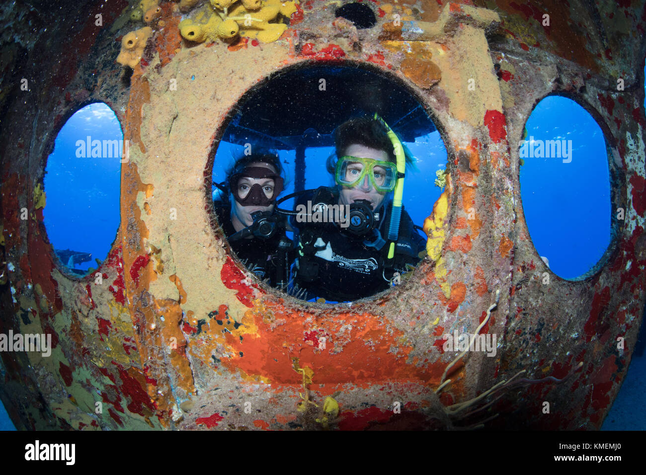 Divers peer through porthole on USS Kittiwake. Stock Photo