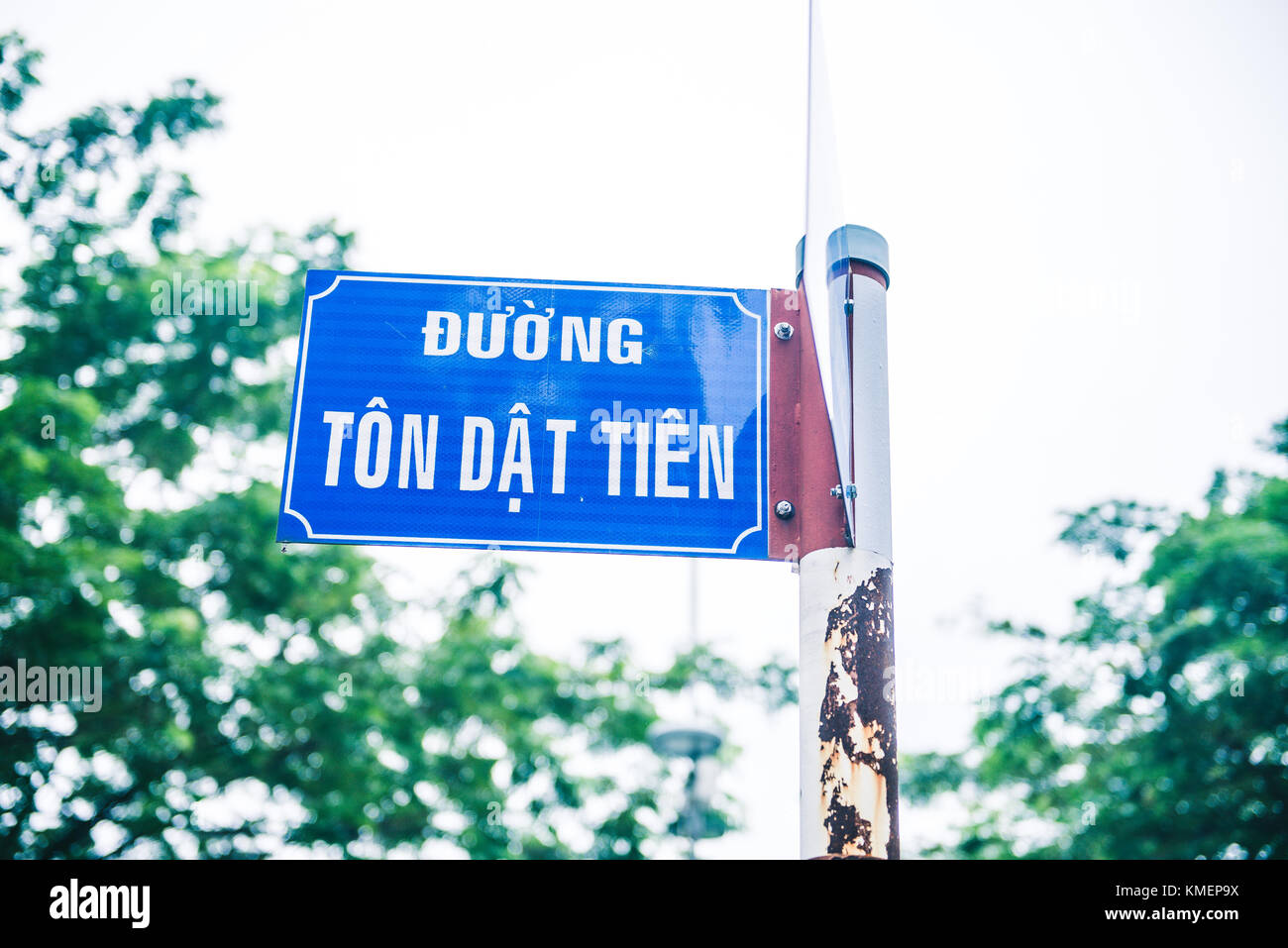 A blue rusted street sign with text "Ton Dat Tien Street" and "Bertrand  Russell street" on a green blue tree background in a cloudy cold day Stock  Photo - Alamy