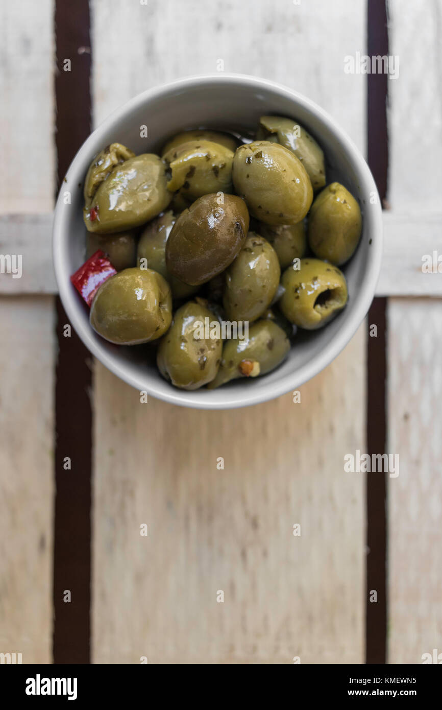 Bowl with delicious olives seasoned on a white background Stock Photo