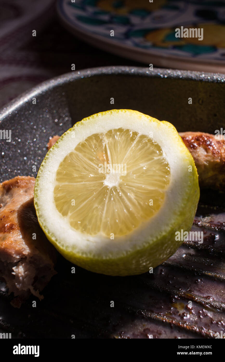 Lemon slice garnishes a grilled sausage Stock Photo