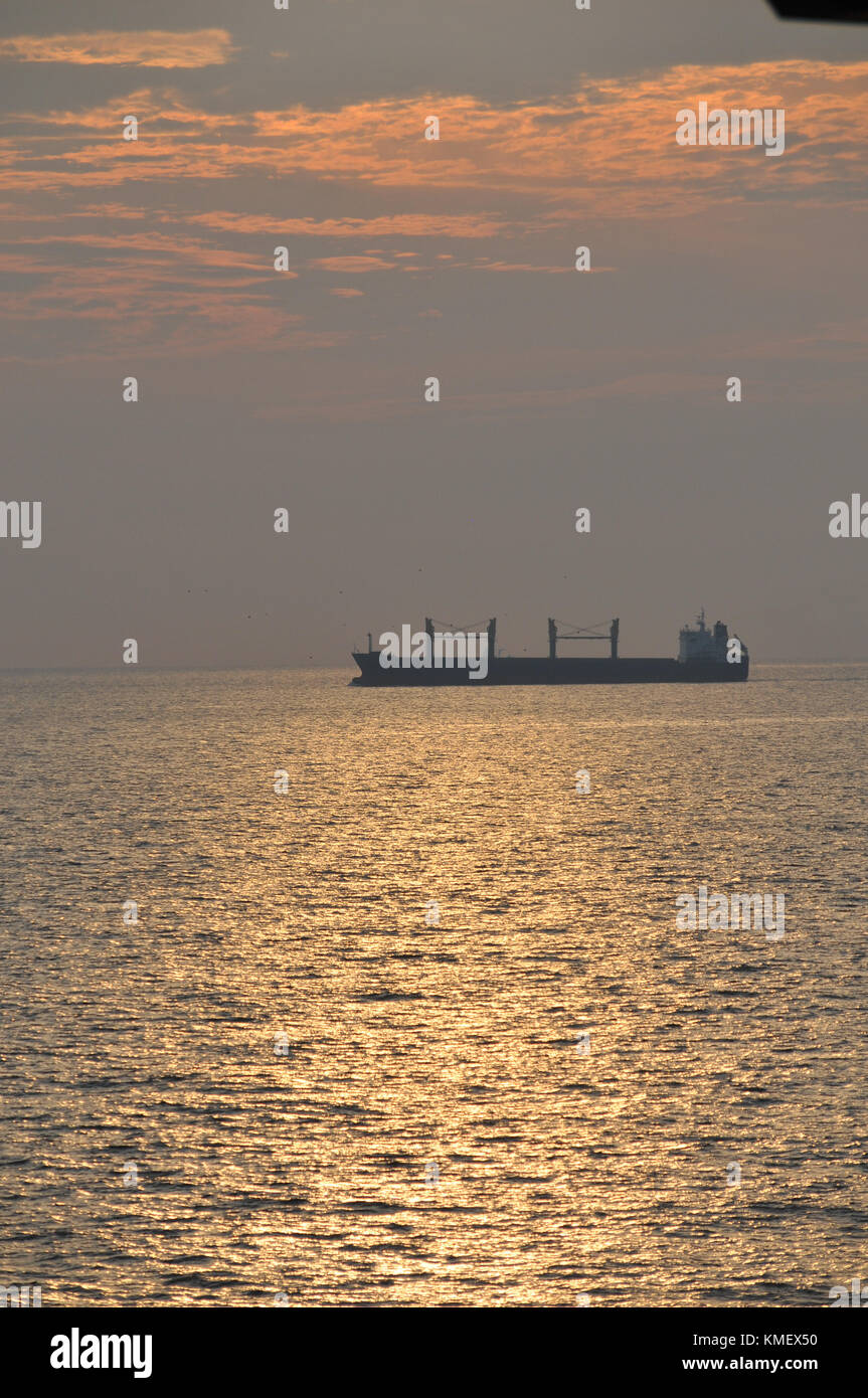 Merchant Ship Silhouette against Setting Sun Stock Photo
