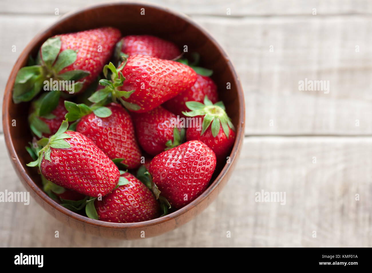 Fresh strawberries in a wooden bowl on a wooden table Stock Photo - Alamy