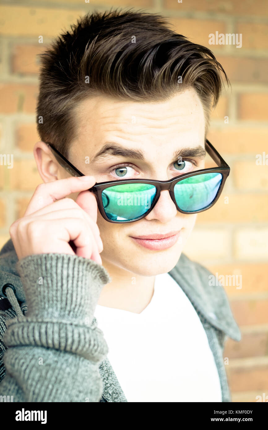 vertical portrait of young man holding sunglasses and looking to the camera Stock Photo