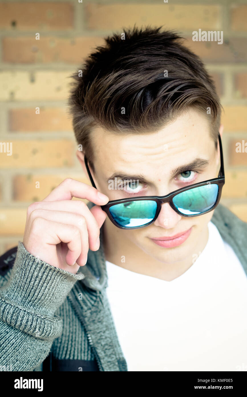 Young man holding fashionable sunglasses and looking to the camera Stock Photo