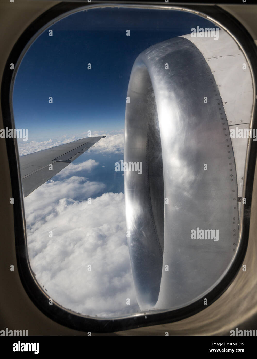 airplane engine and wing seen in flight through cabin window Stock Photo