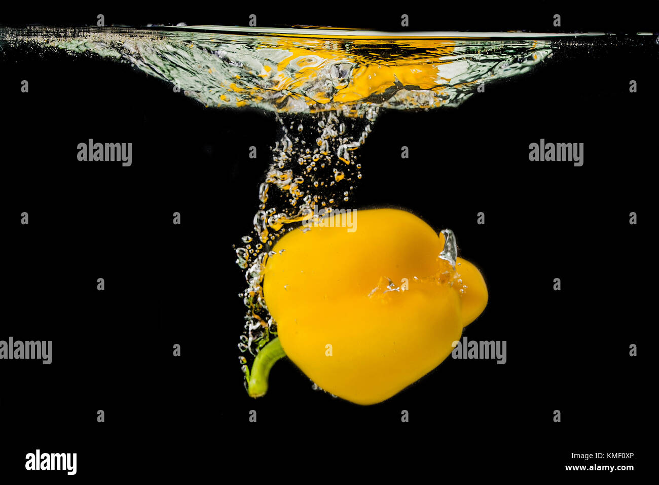 Yellow pepper falls into the water and makes a splash. Stock Photo