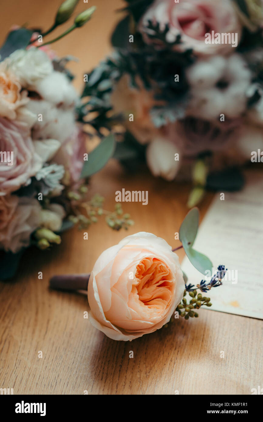 Vertical shot of the lovely light orange rose lying on the posrcard surrounded by colourful flowers. Stock Photo