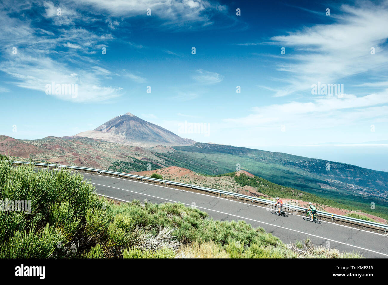 Two cyclists pedaling on mountain road with Mount Teide in background,Teide National Park,Tenerife,Canary Islands,Spain Stock Photo