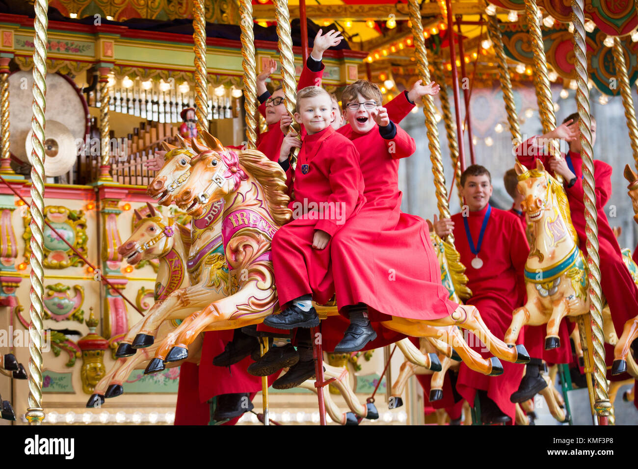 Choristers from Ely Cathedral in Cambridgeshire getting an early Christmas  present as they get a free ride on a 107 year old carousel on Friday afternoon November 17th as the Cathedral holds a Christmas market.  Choristers from Ely Cathedral let off steam on a traditional carousel at the city's Christmas market this afternoon (Fri).  The resident choristers wore their red cassocks as they enjoyed the fairground ride outside the 12th Century Cathedral.  The Ely Christmas Gift and Food Fair is the biggest of its kind in the county and expects to attract 15,000 visitors over the next two days. Stock Photo