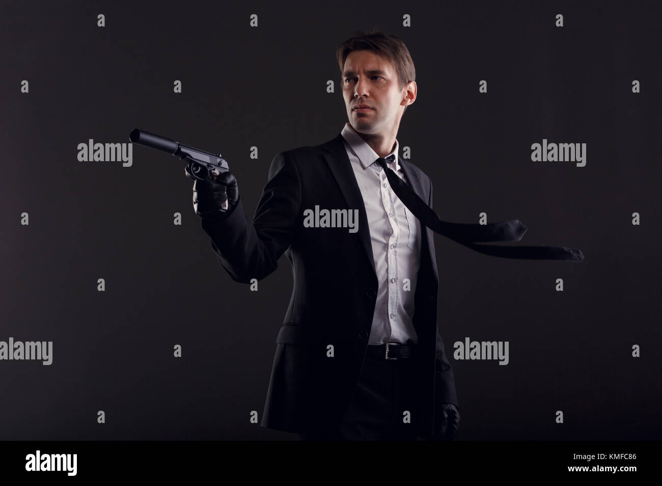 Photo of man with developing tie in leather gloves with gun Stock Photo