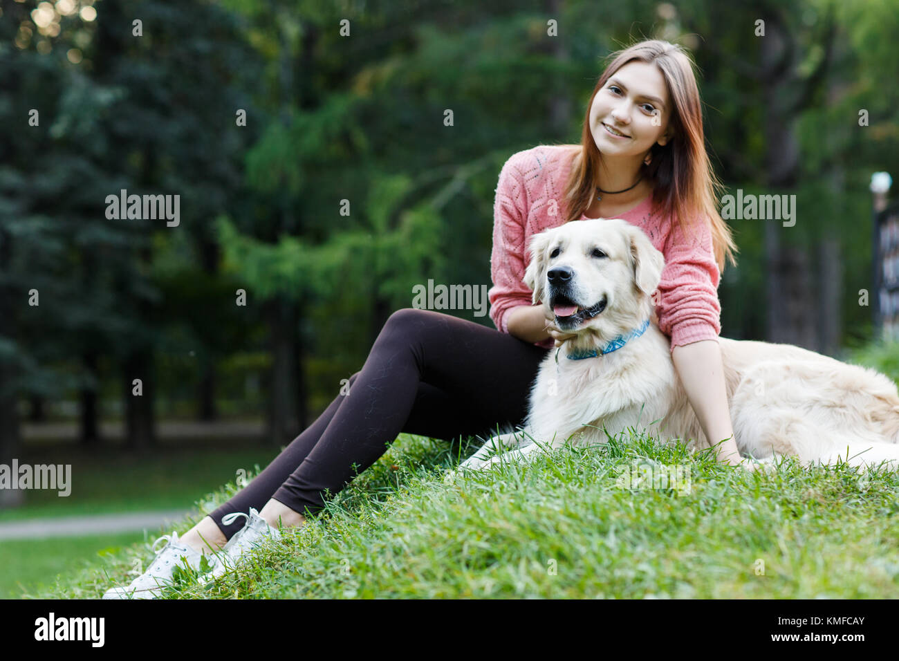 Photo of woman and dog sitting on lawn Stock Photo - Alamy