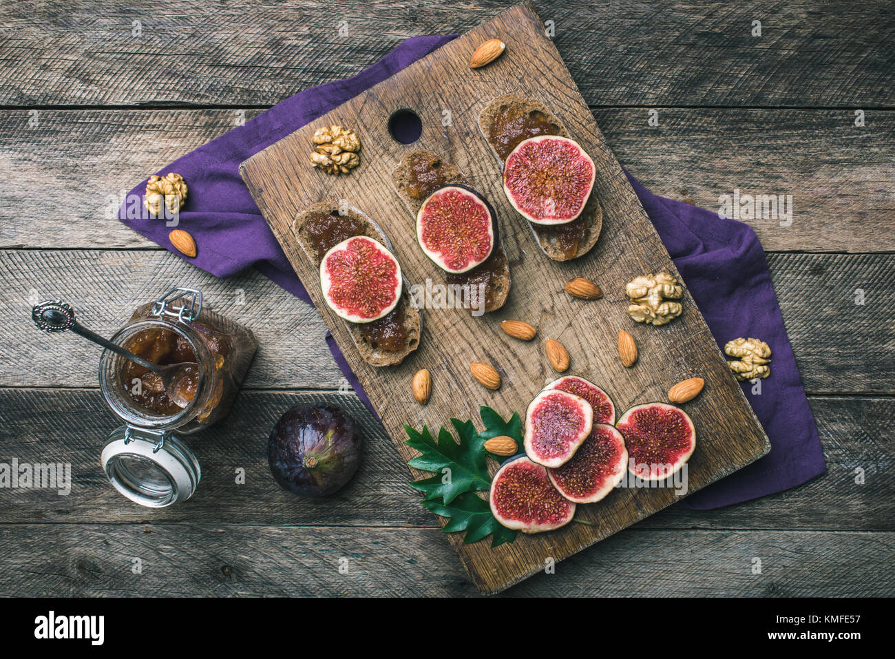 Sliced figs, nuts and bread with jam on wooden choppingboard in rustic style. Autumn season food photo Stock Photo