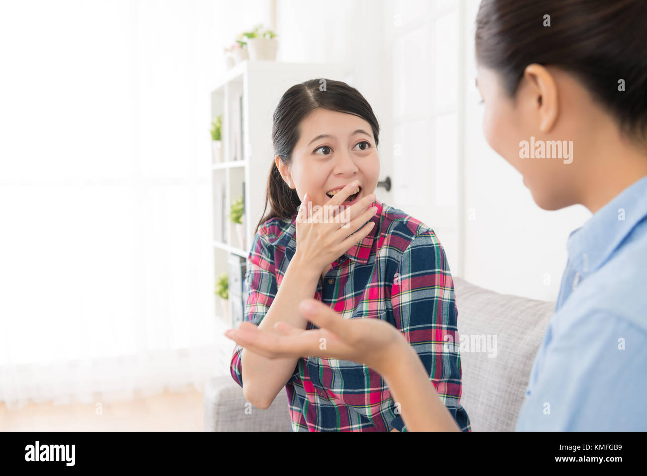 beautiful cheerful girl taking humor joke story for her sister in living room and happy enjoying leisure time together. selective focus photo. Stock Photo