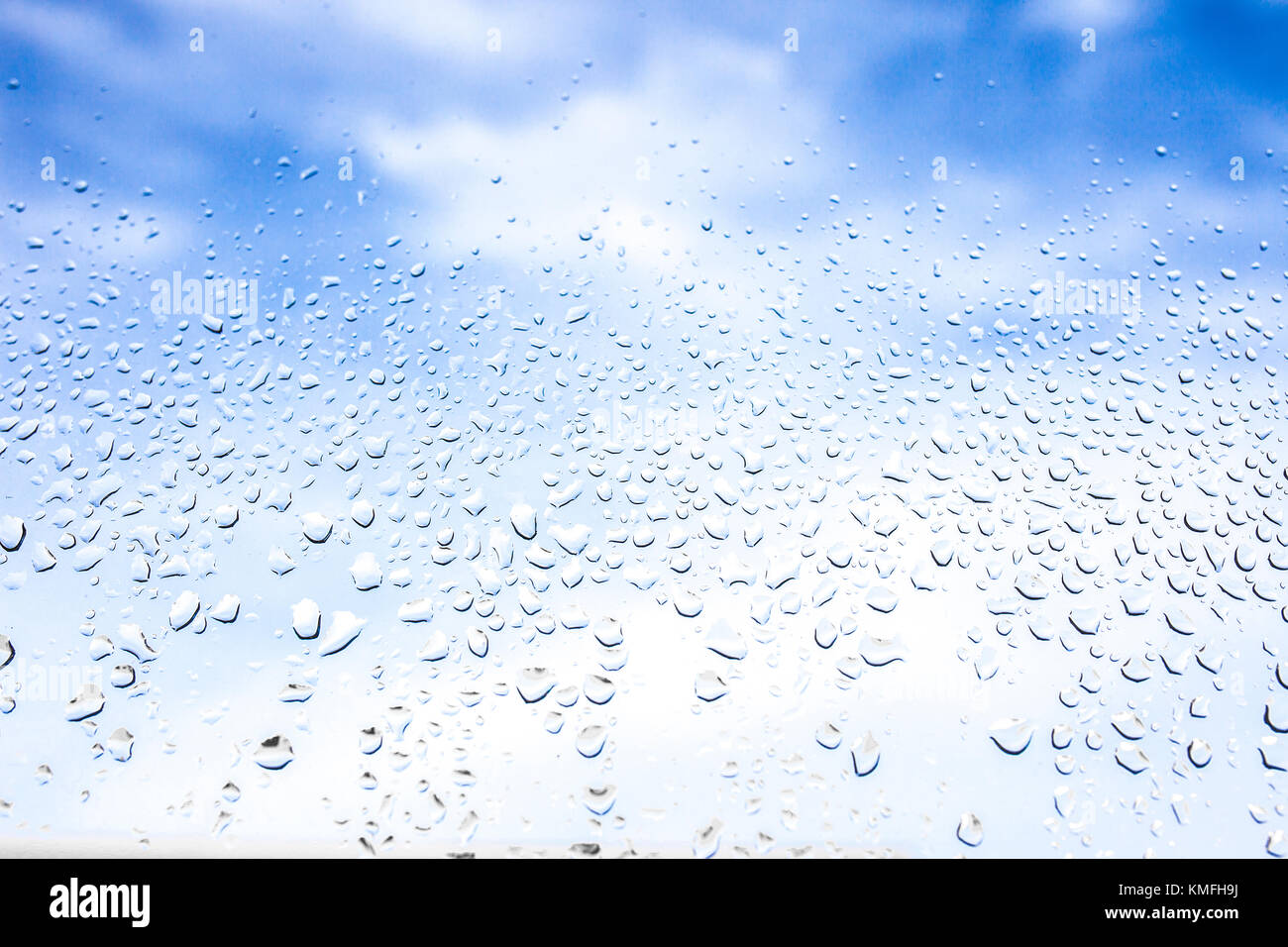 Rain drops on the glass in the background blurred blue cloudy sky. After raining concept Stock Photo