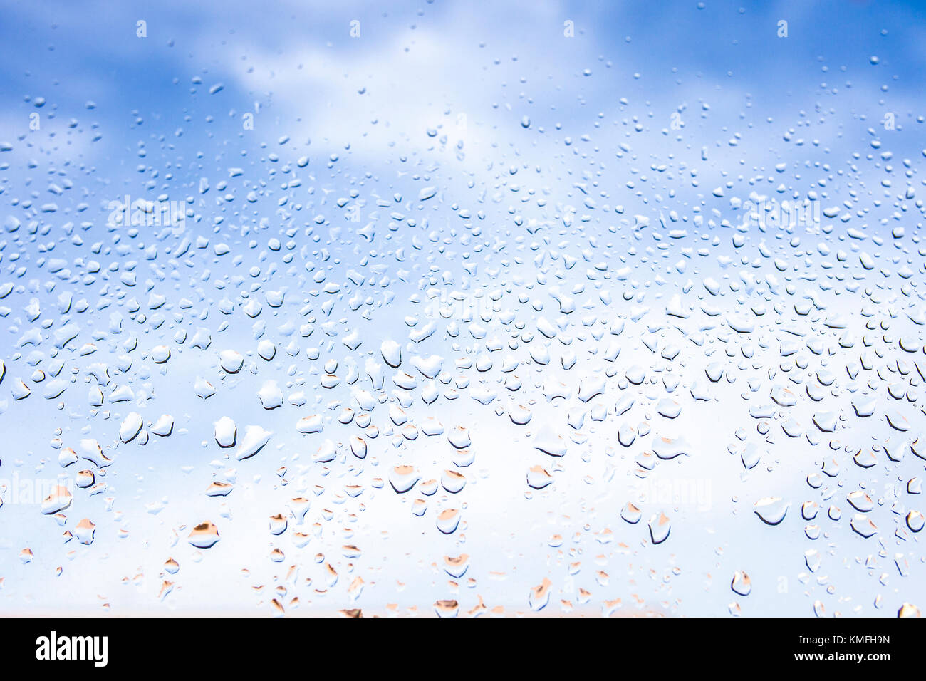 Rain drops on the glass in the background blurred blue cloudy sky. After raining concept Stock Photo