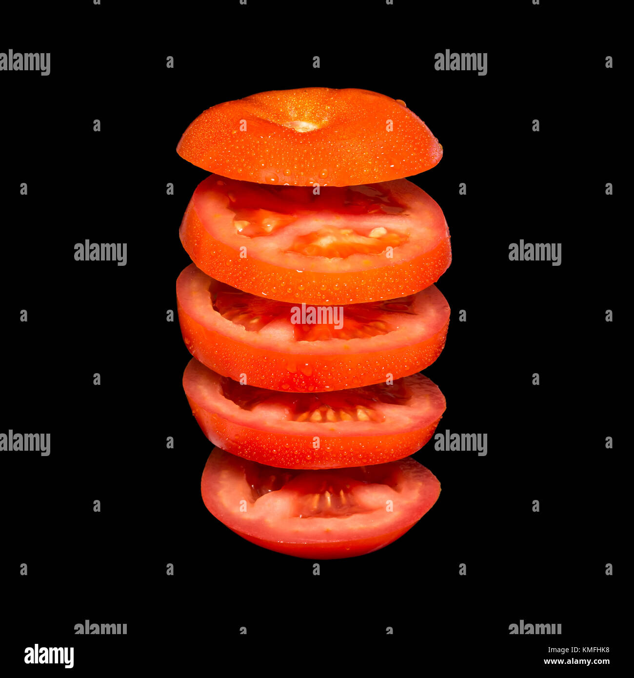Creative concept with flying tomato. Sliced red tomato isolated on black background. Levity vegetable floating in the air. Stock Photo