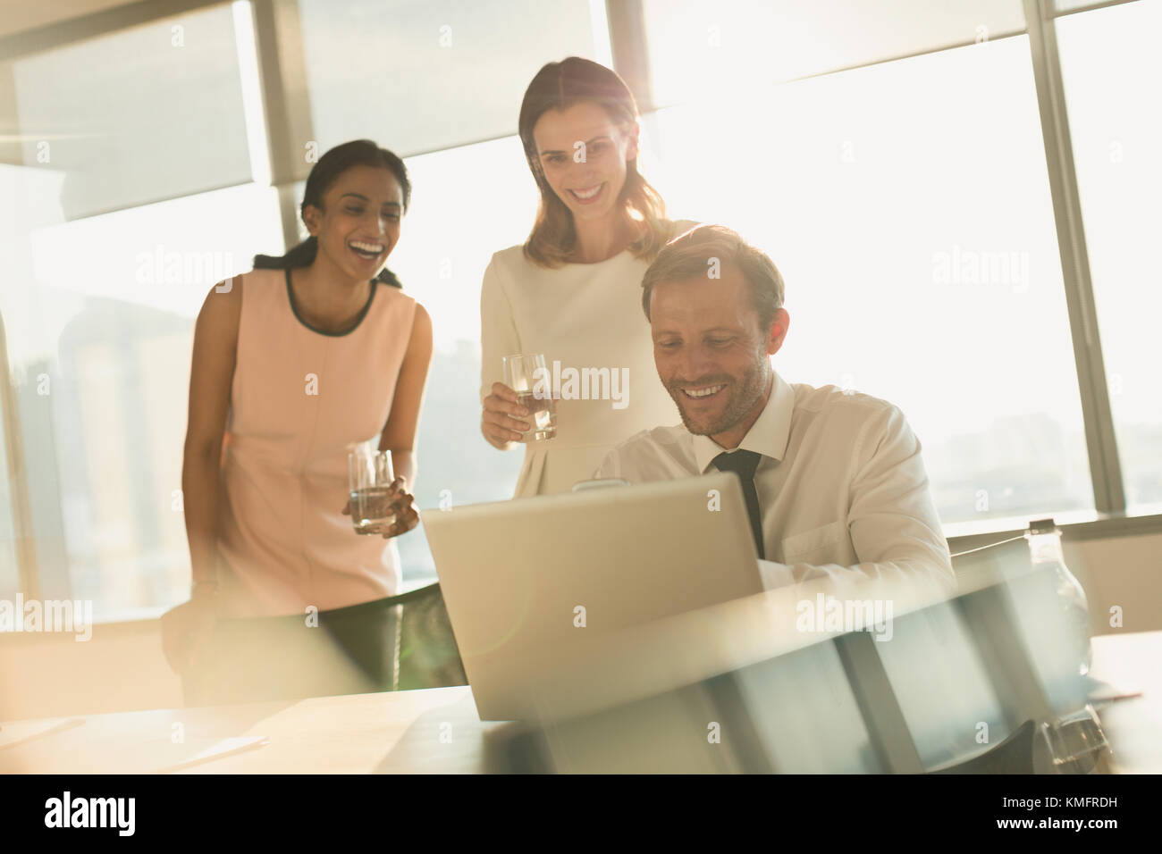 Business people working at laptop in sunny office Stock Photo