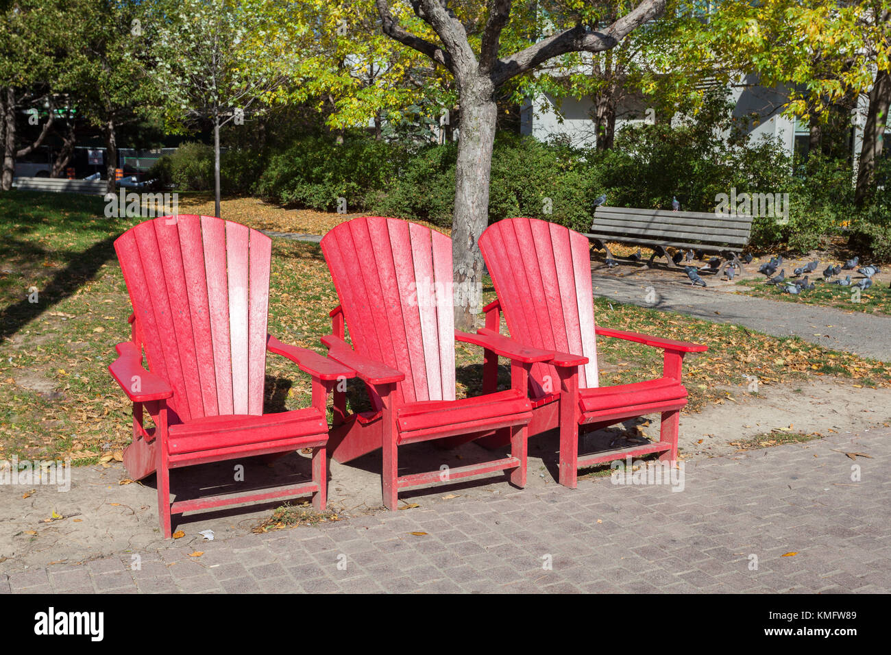Three empty red chairs in an urban park in Toronto, Canada Stock Photo