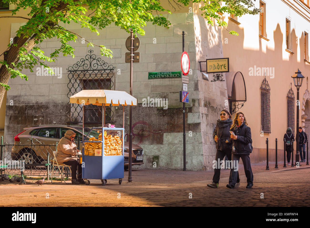 Krakow old town, view of two mature women tourists strolling past a pretzel stand in a square in the old town (Stare Miasto) quarter of Krakow, Poland Stock Photo