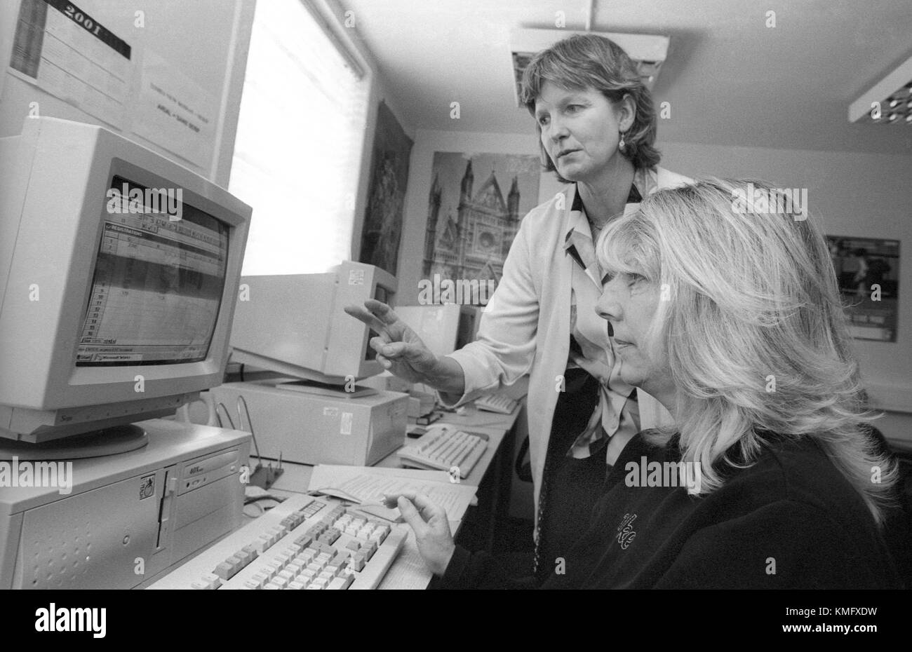 Female inmate learning computer skills in education room assisted by prison tutor (standing) at HMP Winchester prison, Winchester, Hampshire, United Kingdom. 10 May 2001. Stock Photo