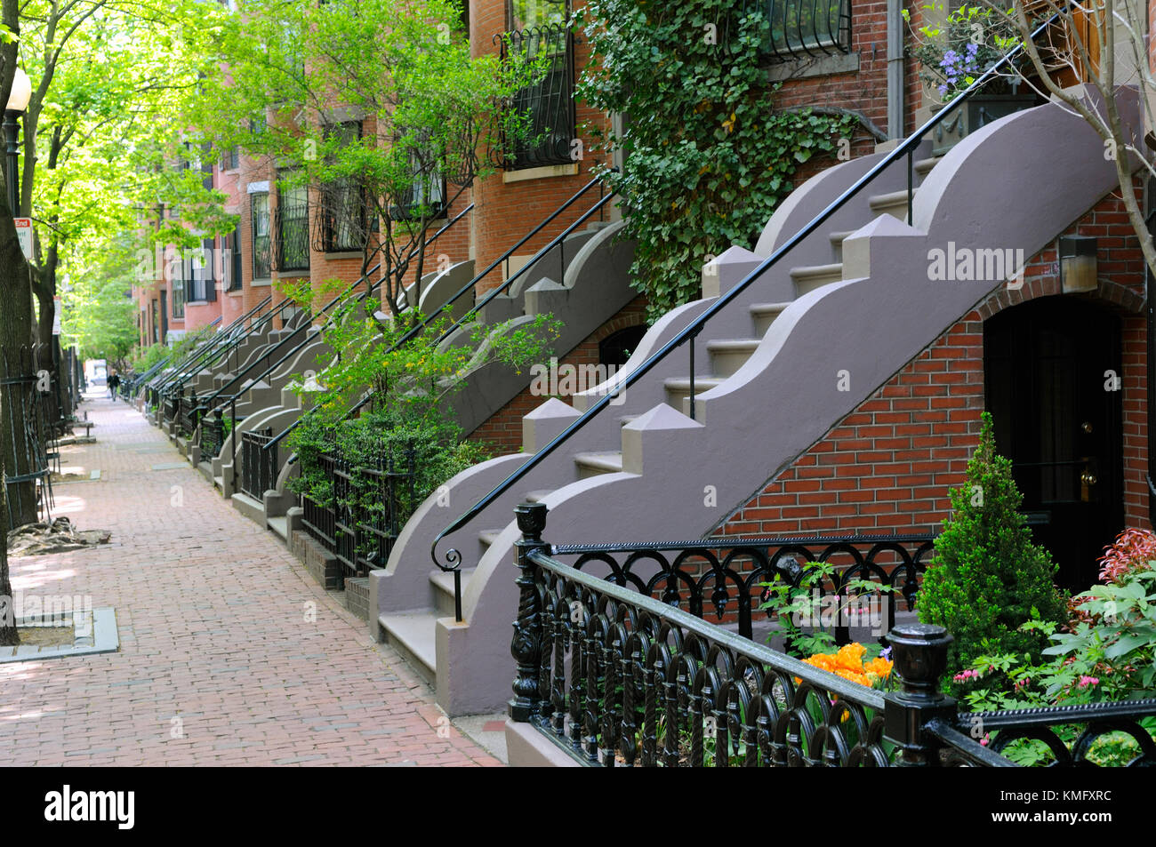 Elegant entry steps of Boston South End row houses. Brick building and sidewalk, iron fences and railings and wavy stone trim on stair side walls. Stock Photo