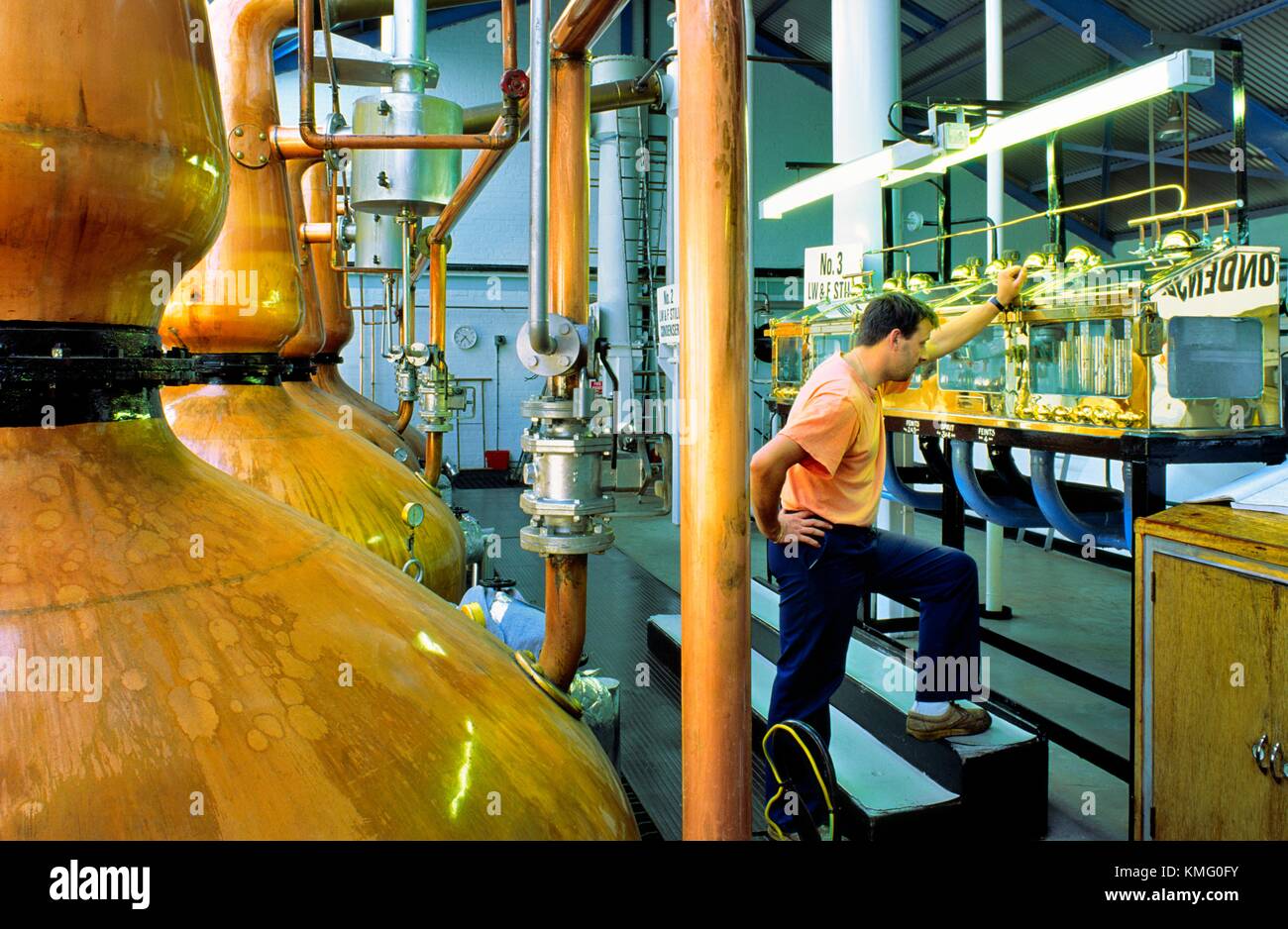 Laphroaig whisky distillery, Isle of Islay, Scotland. Still man checking levels in the spirit safe beside copper pot stills Stock Photo