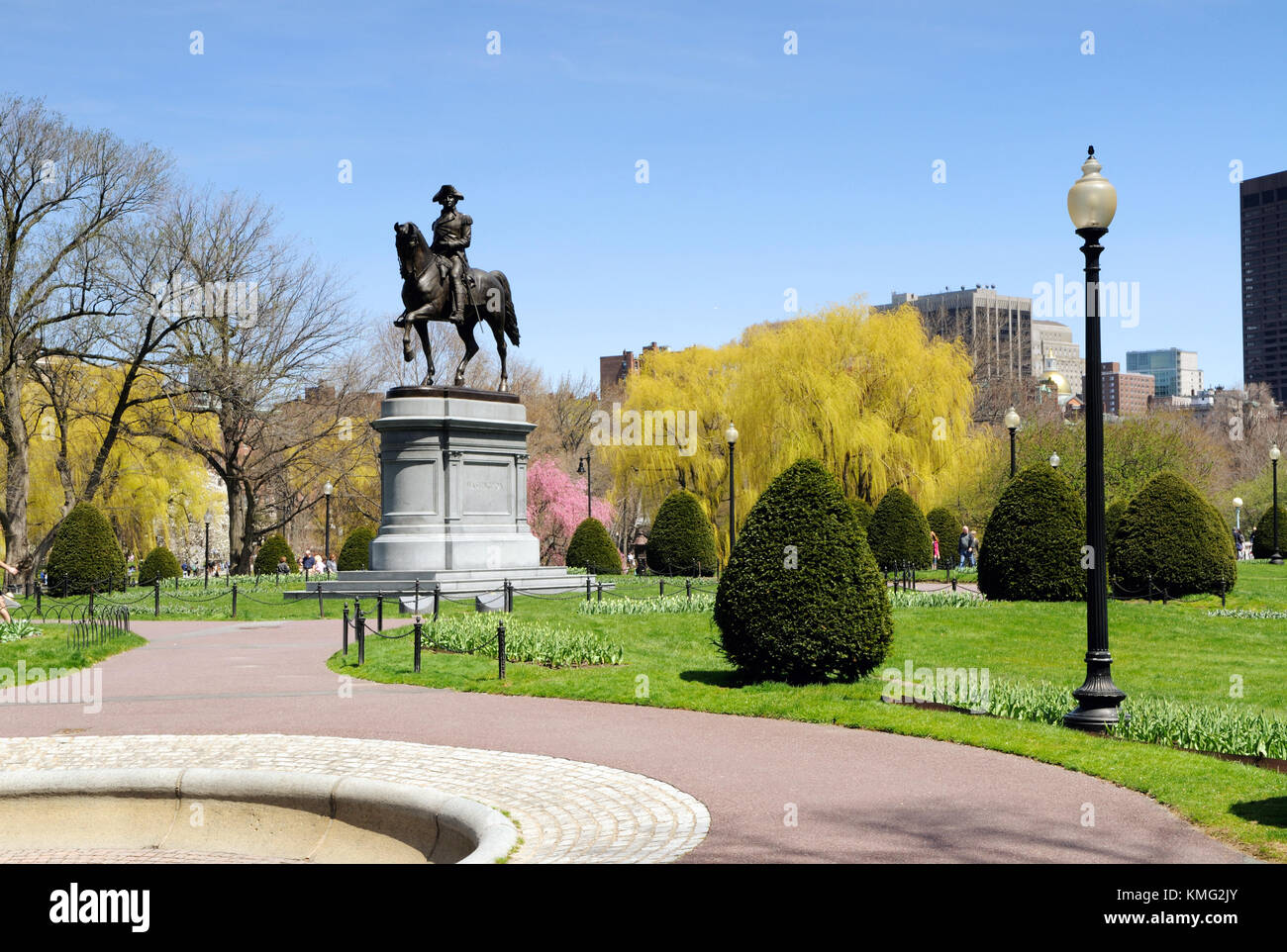 Boston Public Garden in early spring. Colorful tree flowers, meandering paths and George Washington statue. Travel background. Stock Photo